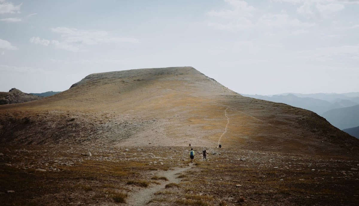 Distant travelers walking on the hillside of the West Highland Way in Scotland.